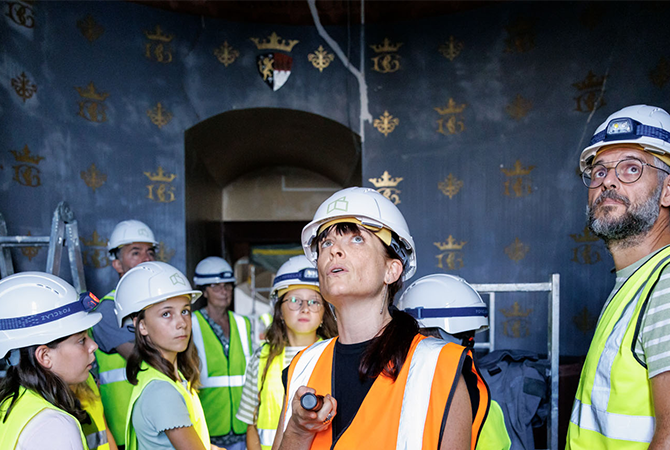 Un groupe visite avec une lampe de poche le chantier du château de Grandson
